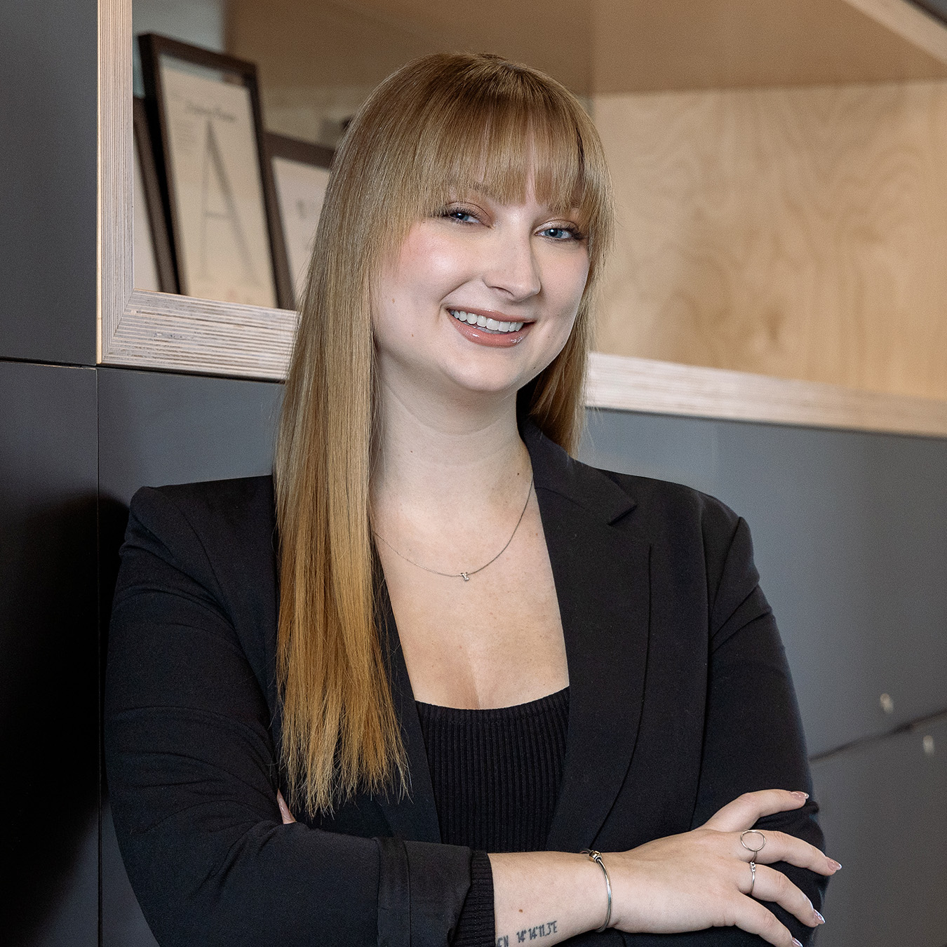 Daliane Bibaud - Une femme aux cheveux longs et châtains très lisses portant un veston noir se tient sur un fond corporatif.